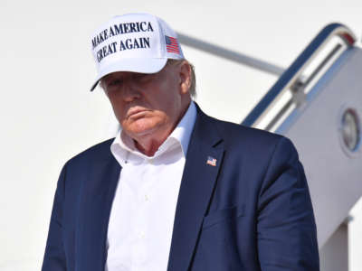 President Trump, wearing a white "Make America Great Again" hat, looks on after stepping off Air Force One on July 26, 2020.