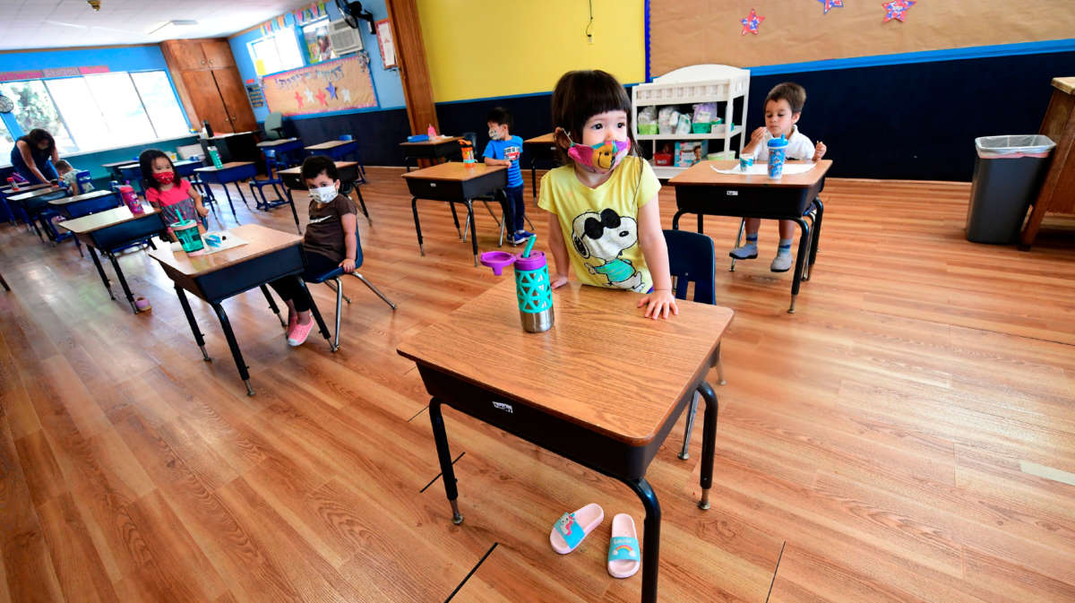 Children in a pre-school class wear masks and sit at desks spaced apart as per coronavirus guidelines during summer school sessions in Monterey Park, California, on July 9, 2020.