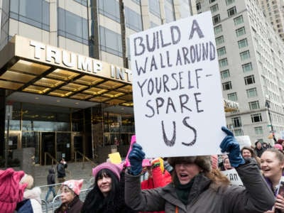 A marcher with a sign that says "Build a Wall Around Yourself - Spare Us" walks in front of Trump International Tower during the Woman's March in the borough of Manhattan in New York City, January 19, 2019.