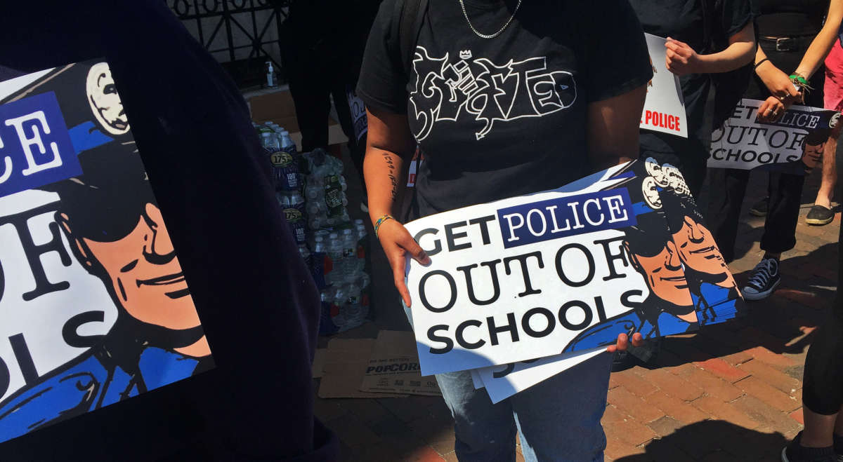 An organizer hands out posters regarding removing police from schools during the For The People youth protest in Nubian Square for a speaking program before marching to City Hall on June 10, 2020, in Boston.