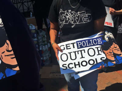 An organizer hands out posters regarding removing police from schools during the For The People youth protest in Nubian Square for a speaking program before marching to City Hall on June 10, 2020, in Boston.