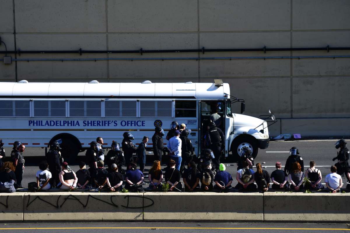 Arrested protesters stand and sit on a barrier of the Vine Street Expressway after police shot tear gas to disperse the crowd on June 1, 2020, in Philadelphia, Pennsylvania.