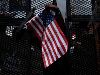 Black Lives Matter protesters remove an American flag as they gather at a closed security checkpoint before a rally that Donald Trump will hold later in the evening at the BOK Center on June 20, 2020, in Tulsa, Oklahoma.