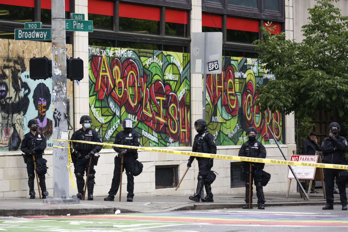 Seattle Police stand in front of graffiti that reads "abolish the cops" and block the entrance to the Capitol Hill Organized Protest (CHOP) after clearing it and retaking the department's East Precinct in Seattle, Washington, on July 1, 2020.