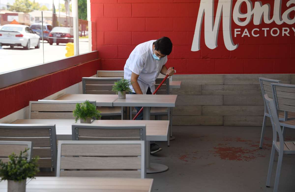 A worker cleans patio tables at the Armenian cuisine restaurant Monta Factory on July 2, 2020, in Glendale, California, after Los Angeles County restaurants were force by state order to shut their doors again to dine-in eating due to a spike in COVID-19 cases.