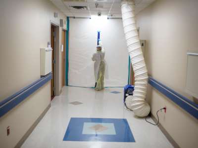 A healthcare worker zips up a protective barrier in the COVID-19 Unit at United Memorial Medical Center in Houston, Texas, on July 2, 2020.