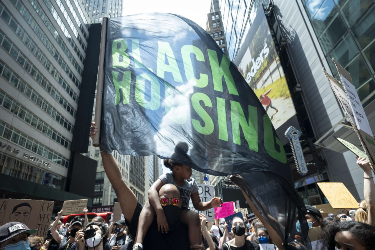 A protester holds a flag with the words "Black Housing" in New York City's Times Square during a Black Lives Matter rally supporting policing, housing and education reforms on June 7, 2020.