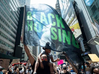 A protester holds a flag with the words "Black Housing" in New York City's Times Square during a Black Lives Matter rally supporting policing, housing and education reforms on June 7, 2020.