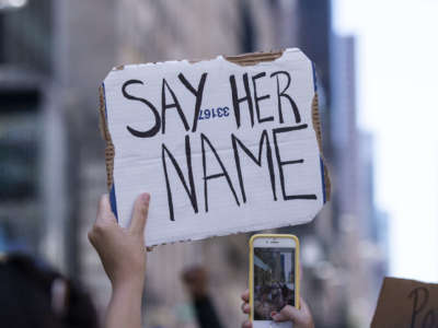 A protester holds up a sign that says, "Say Her Name" while holding their iPhone during the Black Womxn's Empowerment March in New York City on June 12, 2020.