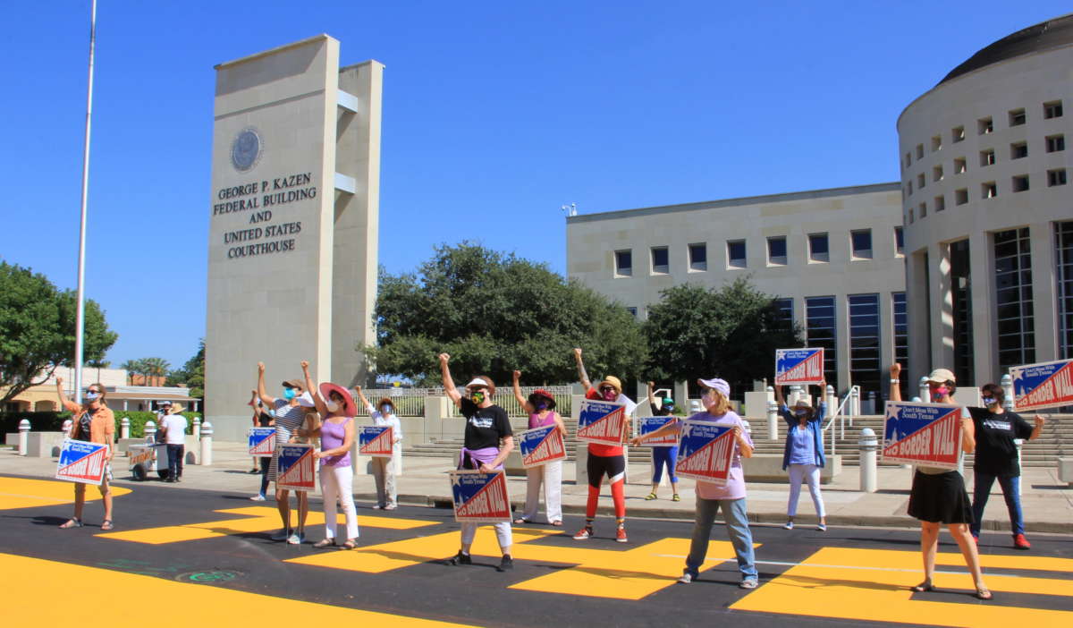 Activists with the No Border Wall Laredo Coalition pose after painting a street mural in front of the George P. Kazen federal building on August 16, 2020.