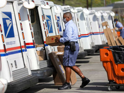 A postal carrier loads mail in his truck for delivery at San Clemente Post Office on May 15, 2020, in San Clemente, California.