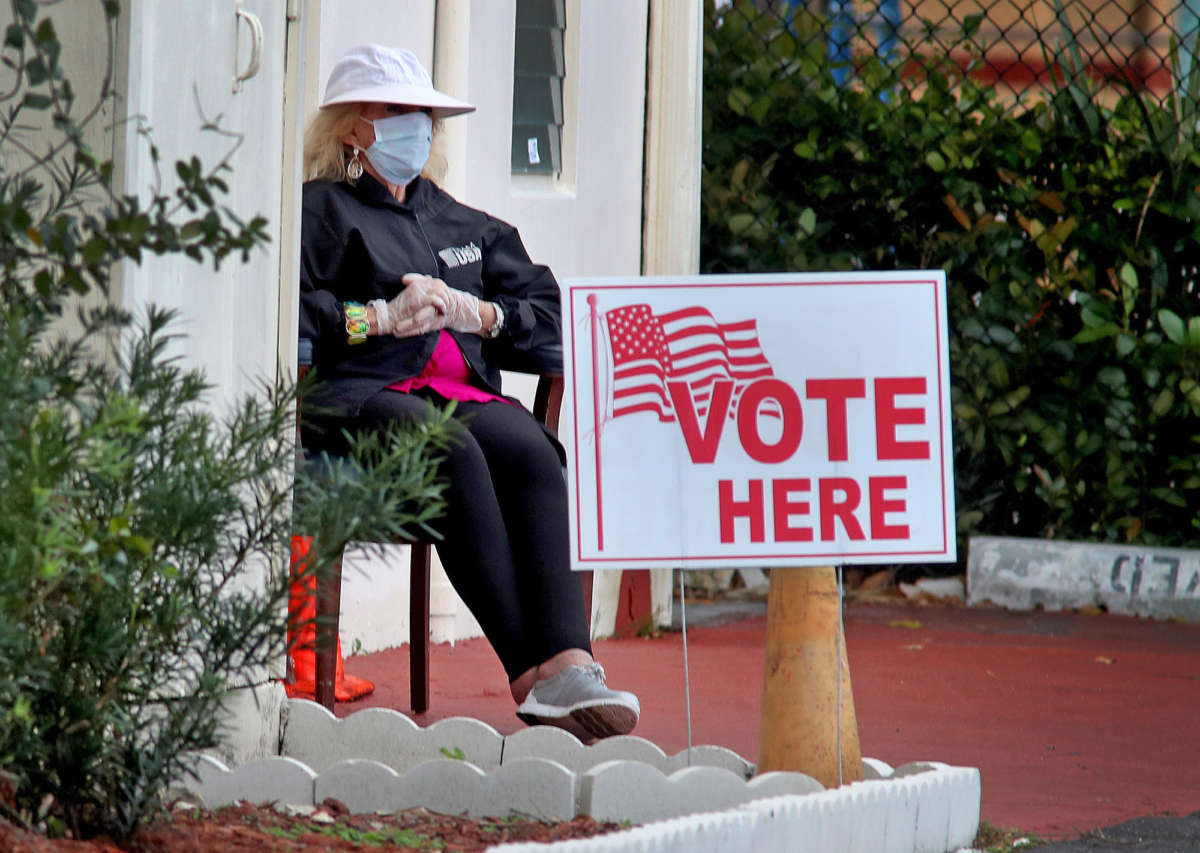 A woman sits in front of the entrance to a polling place