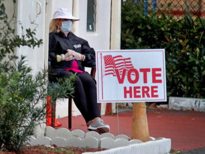 A woman sits in front of the entrance to a polling place