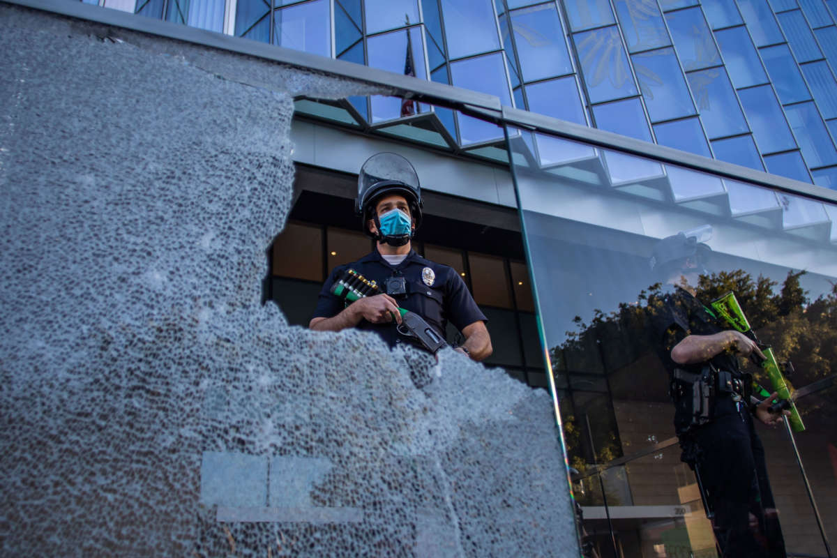 A police officer is seen through a broken glass at the U.S. Courthouse in Downtown Los Angeles, California, on July 25, 2020.
