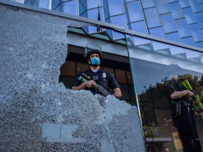 A police officer is seen through a broken glass at the U.S. Courthouse in Downtown Los Angeles, California, on July 25, 2020.