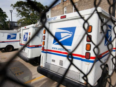 usps trucks sit unused in a chained up parking lot