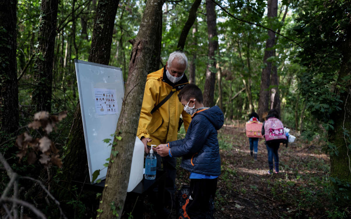 A child cleans his hands during a course in the forest near Upie, France, on May 12, 2020.