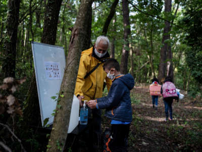 A child cleans his hands during a course in the forest near Upie, France, on May 12, 2020.