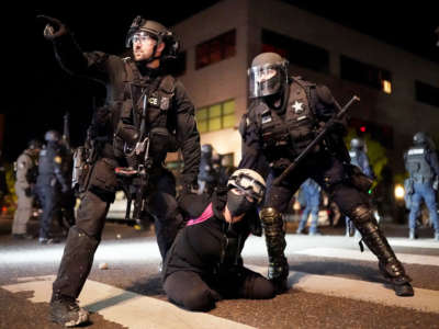 Portland police and Oregon State Patrol officers work together to arrest a protester in front of the Portland Police Bureau North Precinct on the 75th day of protests against racial injustice and police brutality on August 11, 2020, in Portland, Oregon.