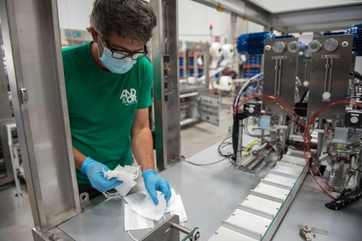 A man in a factory looks at a few medical masks in his hands