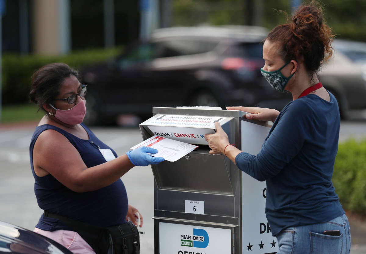 Poll workers at the Miami-Dade County Elections Department deposit peoples' mail in ballots into an official ballot drop box on primary election day on August 18, 2020, in Doral, Florida.