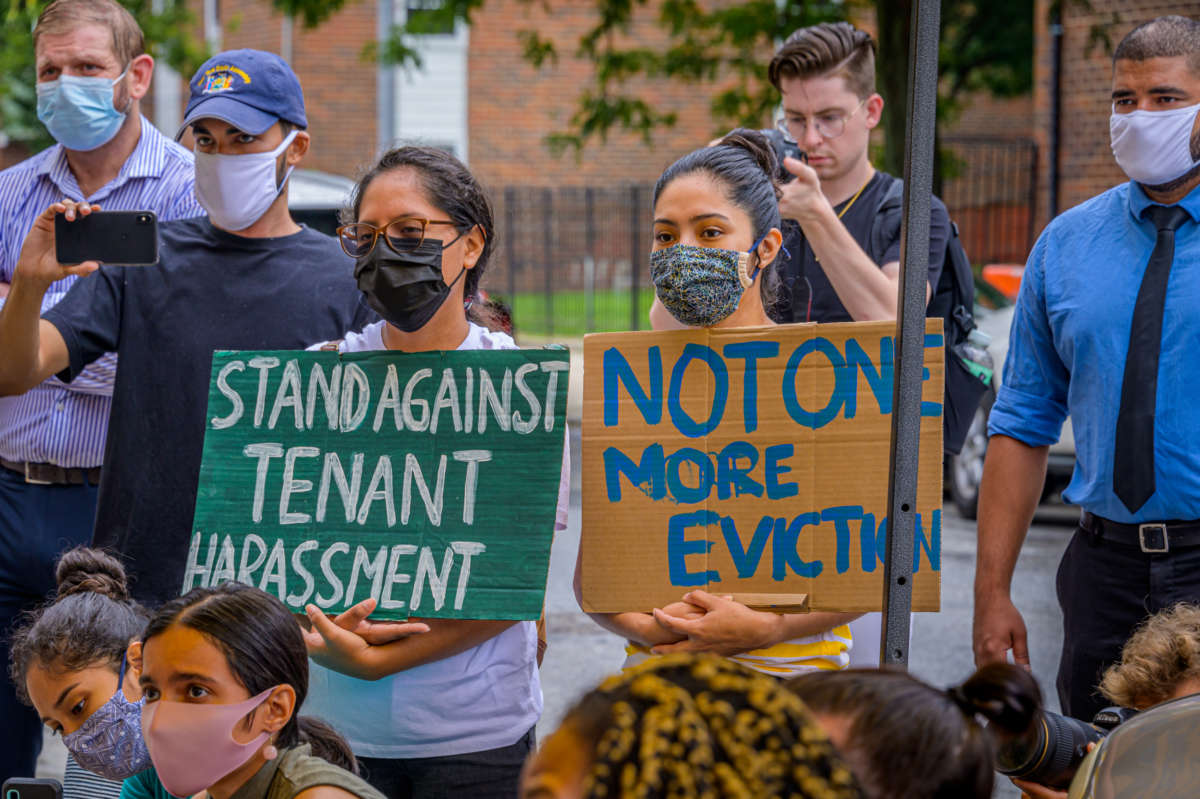 activists display signs reading "STAND AGAINST TENANT HARASSMENT" and "NOT ONE MORE EVICTION" at a protest