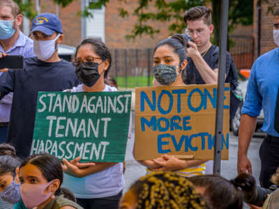 activists display signs reading "STAND AGAINST TENANT HARASSMENT" and "NOT ONE MORE EVICTION" at a protest