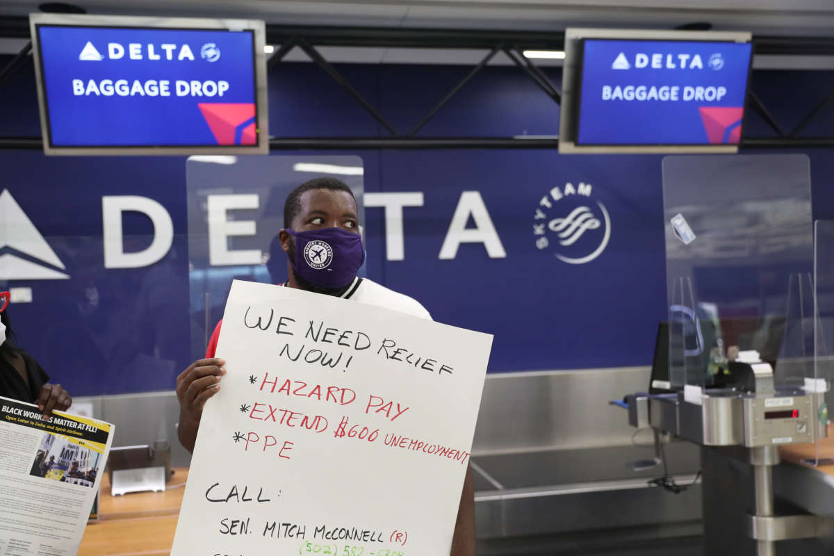 An airport worker demonstrates in front of the Delta Airlines kiosk while displaying a sign