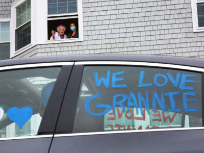Eleanor Dittmer, joined in the window by nurse's aide Courtney Nadeau at the Harriett and Ralph Kaplan Estates in Peabody, Massachusetts, has a drive-by birthday party in the parking lot of the facility on April 26, 2020.