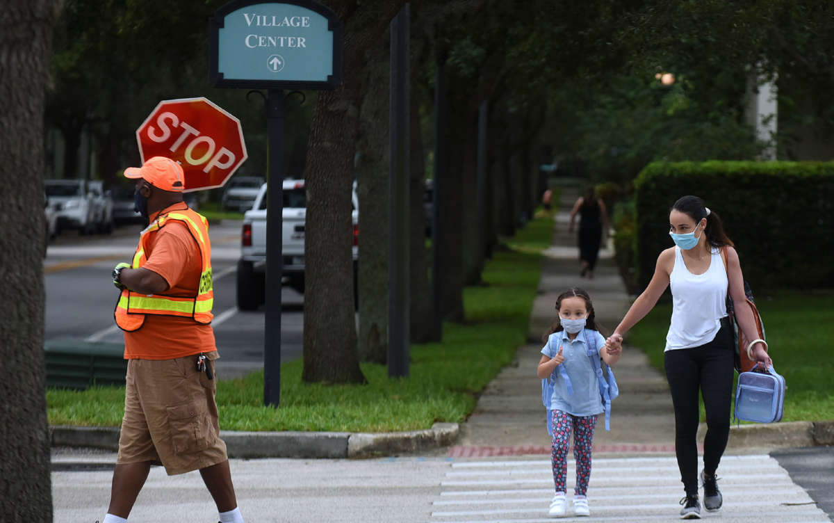 A mother walks her child to school on the first day of in-person classes in Orange County at Baldwin Park Elementary School on August 21, 2020, in Orlando, Florida.