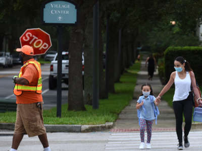 A mother walks her child to school on the first day of in-person classes in Orange County at Baldwin Park Elementary School on August 21, 2020, in Orlando, Florida.