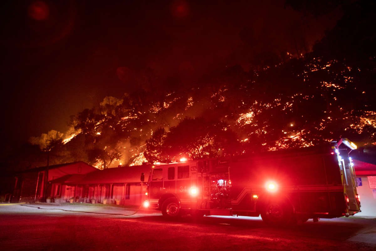 A fire engine is parked in front of the Canyon Creek Resort as the the LNU Lightning Complex wildfire burns a hillside behind it in Winters, California, August 20, 2020.