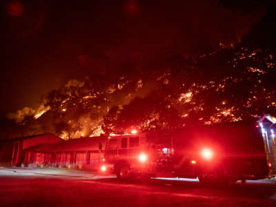 A fire engine is parked in front of the Canyon Creek Resort as the the LNU Lightning Complex wildfire burns a hillside behind it in Winters, California, August 20, 2020.