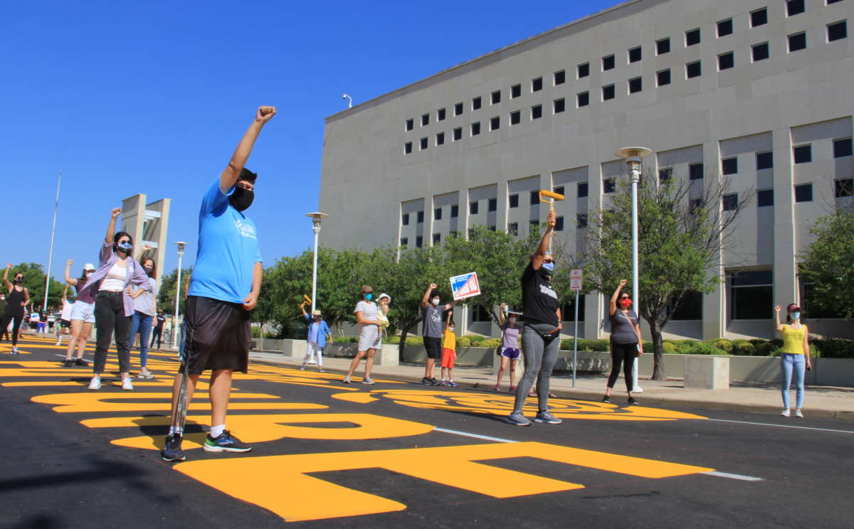 Activists with the No Border Wall Laredo Coalition pose after painting a street mural in front of the George P. Kazen federal building on August 16, 2020.