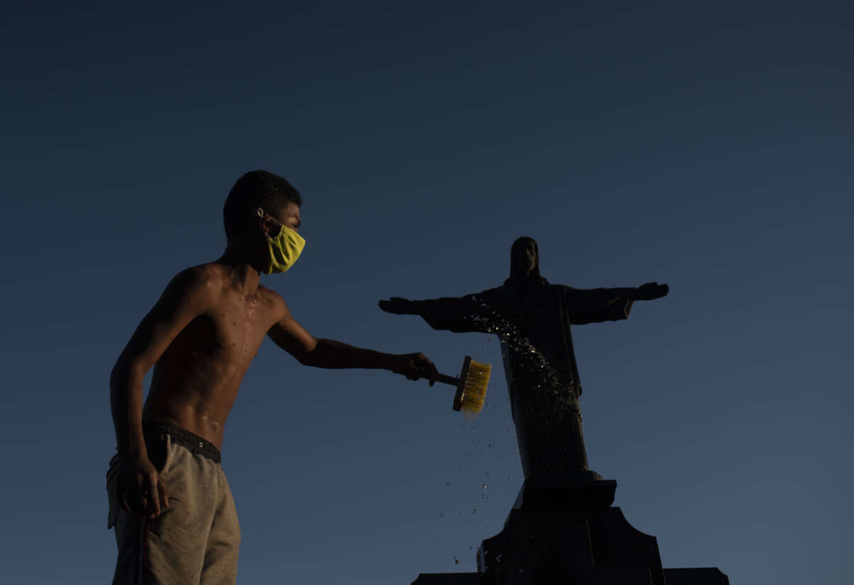 Josué Vicente Pereira cleans a statue on the grave of a traditional, wealthy family.