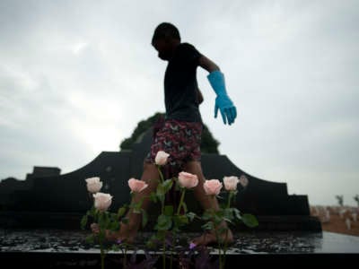 Josué Vicente Pereira cleaning a grave made of black marble in the Caju Cemetery in Rio de Janeiro, Brazil.