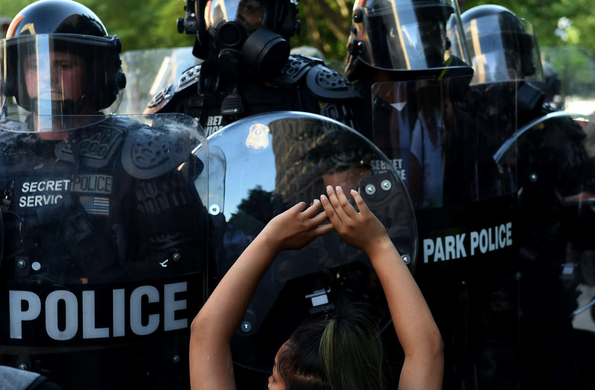 A protester kneels and holds up their hands in front of a row of police during a demonstration against the death of George Floyd at a park near the White House on June 1, 2020, in Washington, D.C.