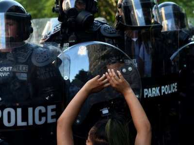 A protester kneels and holds up their hands in front of a row of police during a demonstration against the death of George Floyd at a park near the White House on June 1, 2020, in Washington, D.C.