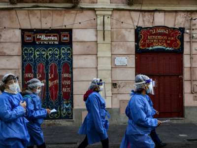 Health workers walk at Caminito street after visiting people suspected of having COVID-19 at La Boca neighbourhood in Buenos Aires, on July 9, 2020, amid the new coronavirus pandemic.