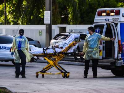 Medics transfer a patient on a stretcher from an ambulance outside of the emergency room at Coral Gables Hospital where Coronavirus patients are treated in Coral Gables near Miami, on July 30, 2020.