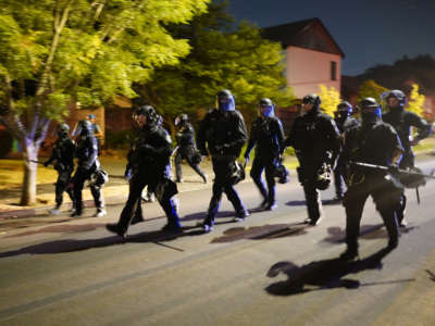 Portland police officers pursue a crowd of about 200 protesters after dispersing the group from in front of the Multnomah County Sheriff's Office on August. 1, 2020, in Portland, Oregon.