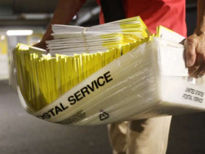 A polling worker holds 2020 presidential primary ballots that were dropped at a post office and brought to a government center to be processed and counted at the Stamford Government Center on August 11, 2020, in Stamford, Connecticut.