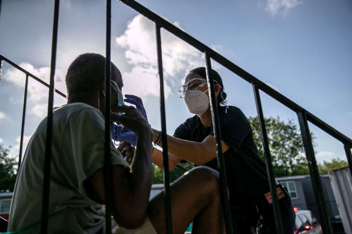 Medics with the Houston Fire Department provide oxygen to a patient with trouble breathing before taking him to the hospital on August 14, 2020, in Houston, Texas.