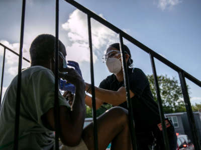 Medics with the Houston Fire Department provide oxygen to a patient with trouble breathing before taking him to the hospital on August 14, 2020, in Houston, Texas.