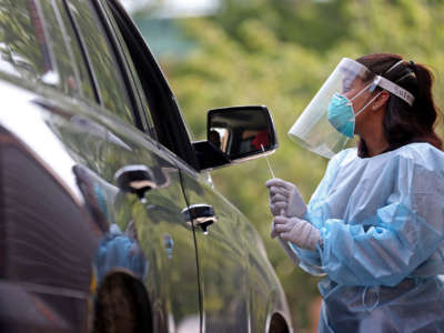 A medical assistant takes a swab sample from a patient at a COVID-19 testing site at the Bunker Hill Housing Development on August 11, 2020, in Charlestown, Massachusetts.