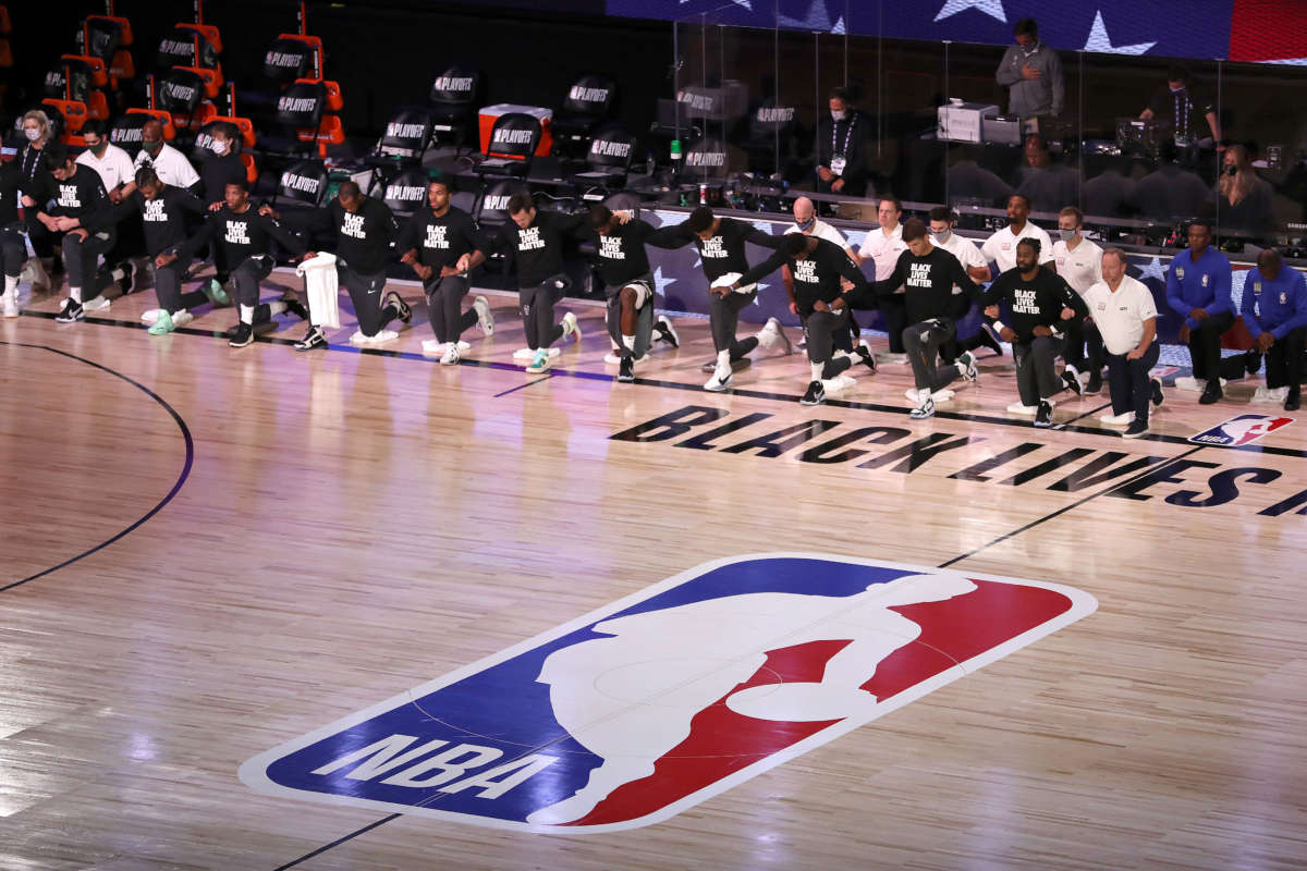 The Miami Heat and the Milwaukee Bucks kneel during the National Anthem prior to the start of a game during the 2020 NBA Playoffs at the Field House at ESPN Wide World Of Sports Complex on September 2, 2020, in Lake Buena Vista, Florida.