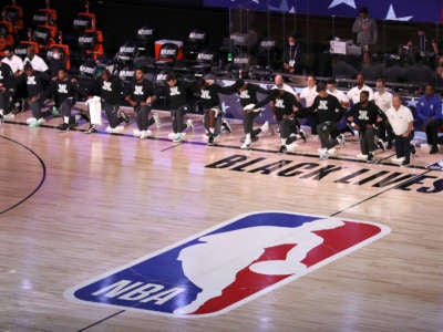 The Miami Heat and the Milwaukee Bucks kneel during the National Anthem prior to the start of a game during the 2020 NBA Playoffs at the Field House at ESPN Wide World Of Sports Complex on September 2, 2020, in Lake Buena Vista, Florida.