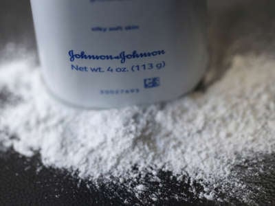 A container of Johnson's baby powder made by Johnson and Johnson sits on a table.