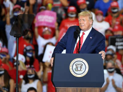 Donald Trump leans on his podium and makes a face somewhere between a smile and a sneer