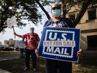 A protester wearing a face mask holds a placard in support of the U.S. Postal Service during a demonstration in Dayton, Ohio, August 25, 2020.